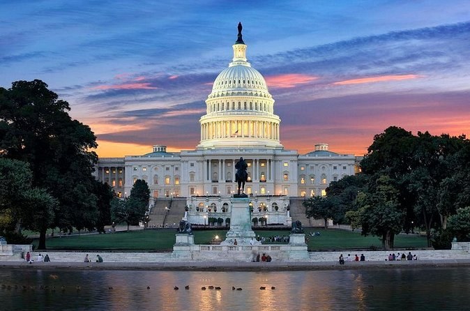 The Capitol's west front under a sunset sky, the pool in front