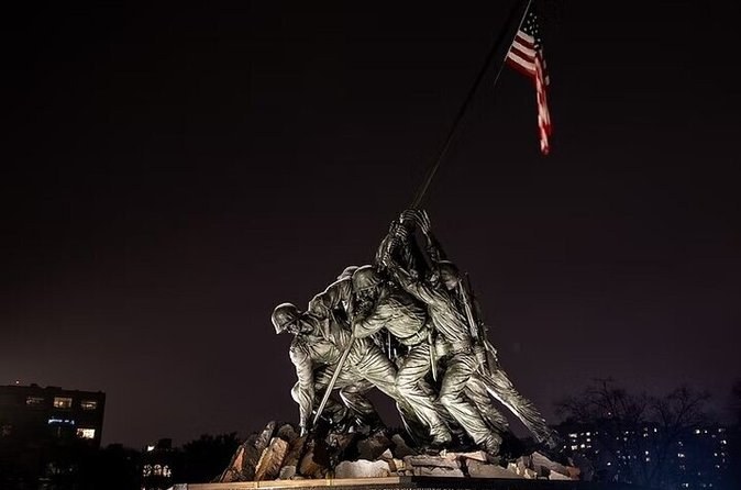 The bronze flag raisers and their flag, which flies day and night, lit after dark