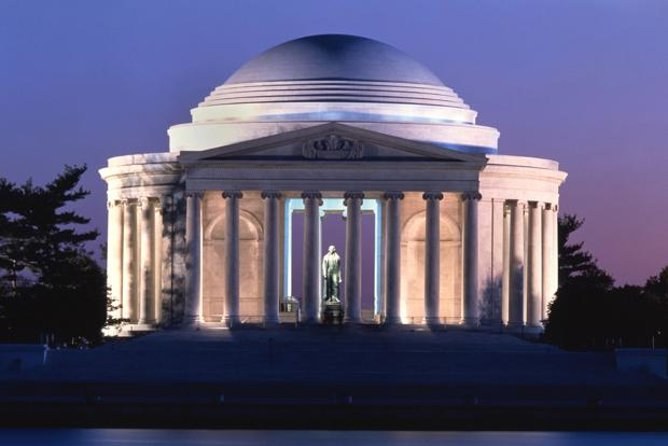 A domed memorial lit at dusk, its statue visible between the columns