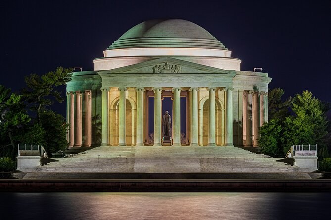 A domed memorial's portico and statue lit up at night