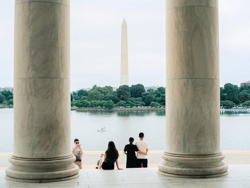 The Washington Monument framed between two memorial columns across the water